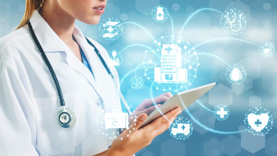 Ärztin mit einem Tablet in der Hand, über dem Tablet verschiedene Symbole aus dem Krankenhausbereich