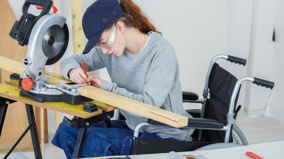 Frau im Rollstuhl an einer Handwerksbank