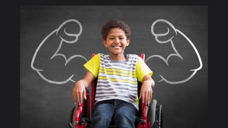 Junge im Rollstuhl, dahinter an der Tafel gemalte starke Arme