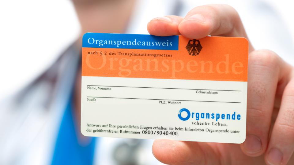 Mediziner hält Organspendeausweis in die Kamera