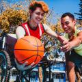 Ein junger Mann im rollstuhl spielt Basketball mit einem jungen Mann ohne Einschränkungen