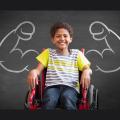 Junge im Rollstuhl, dahinter an der Tafel gemalte starke Arme