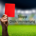 Im Hintergrund sieht man verschwommen die Ränge eines Fußballstadions und deutlich den grünen Rasen. Im Vordergrund sieht man eine männliche Hand, die eine rote Karte hochhält. Daneben steht "Stopp Diskriminierung".