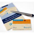  Auf der untersten rechten Ecke einer Broschüre zum Thema Organspendeausweis liegt ein Organspendeausweis. Oberhallb des ausweises liegt ein silberner Kugelschreiber ebenfalls halb auf der Broschüre.